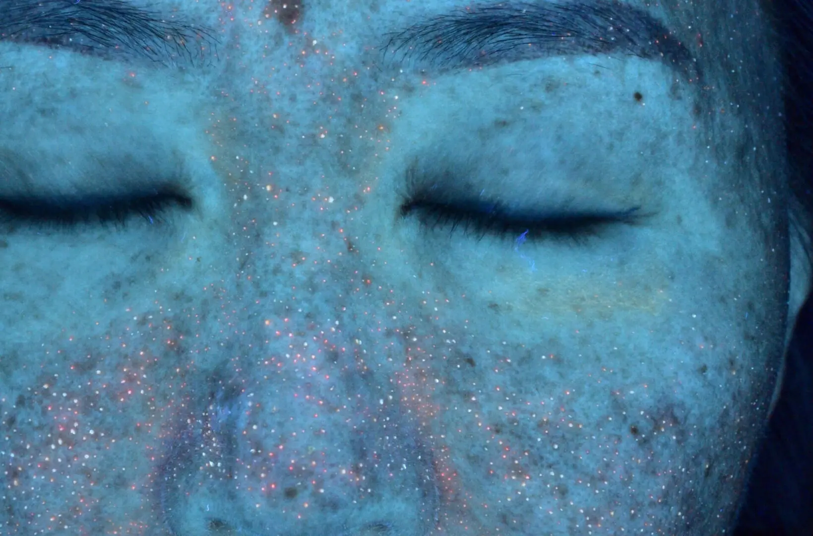 A close up of the face of a person with blue makeup.