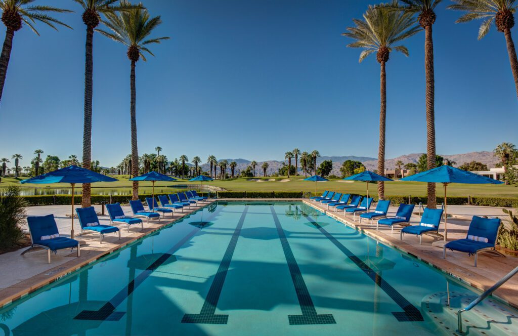 A pool with many chairs and umbrellas in the middle of it