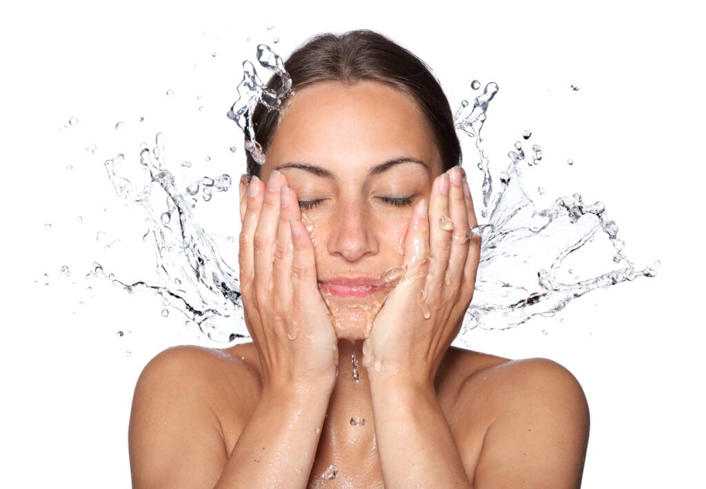 A woman with her hands on her face in front of water.