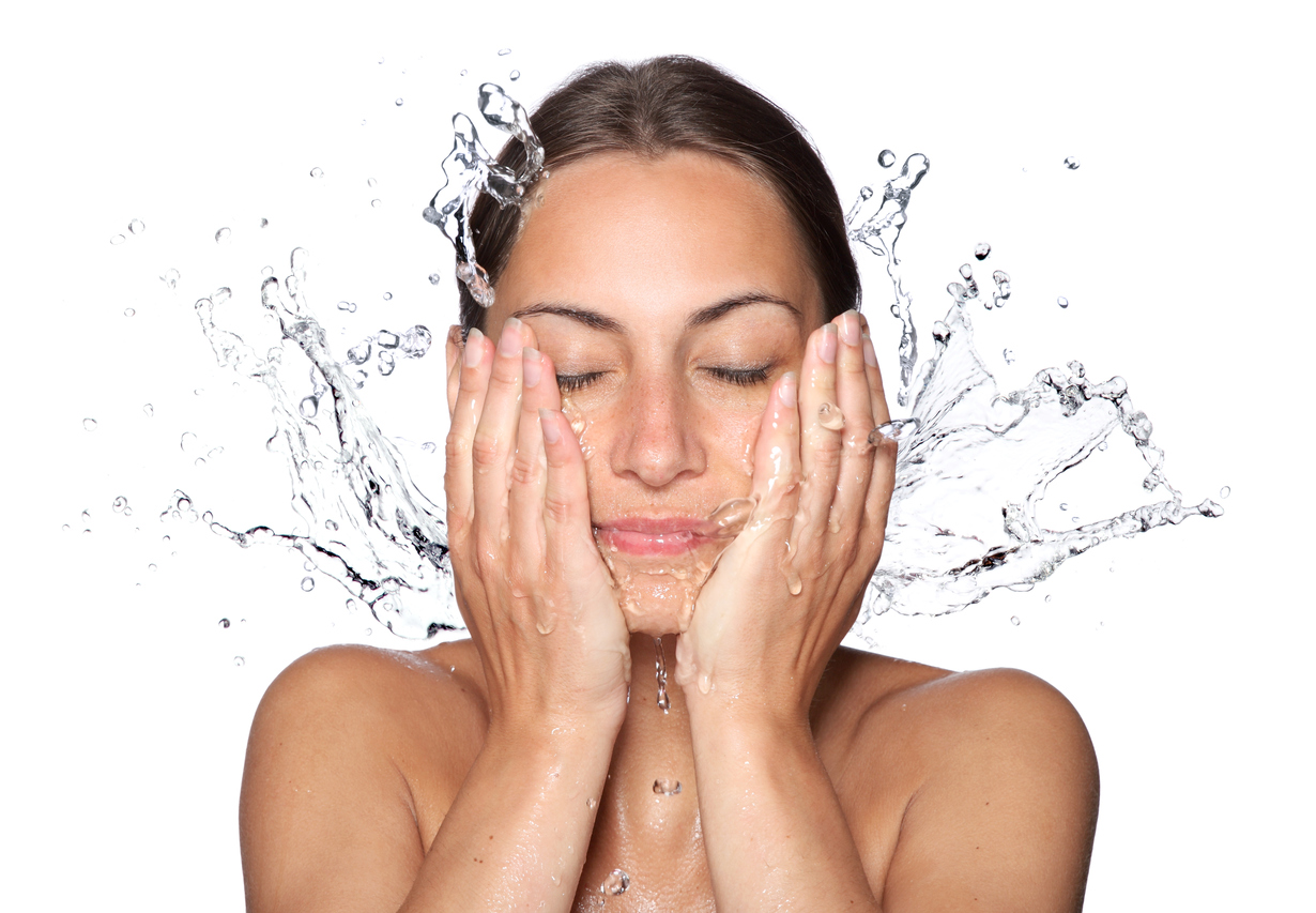 A woman with her hands on her face in front of water.