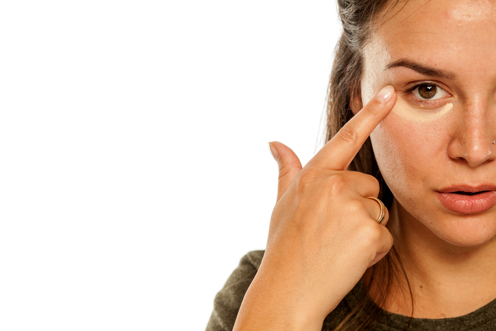 A woman holding her finger to the temple of her eye.