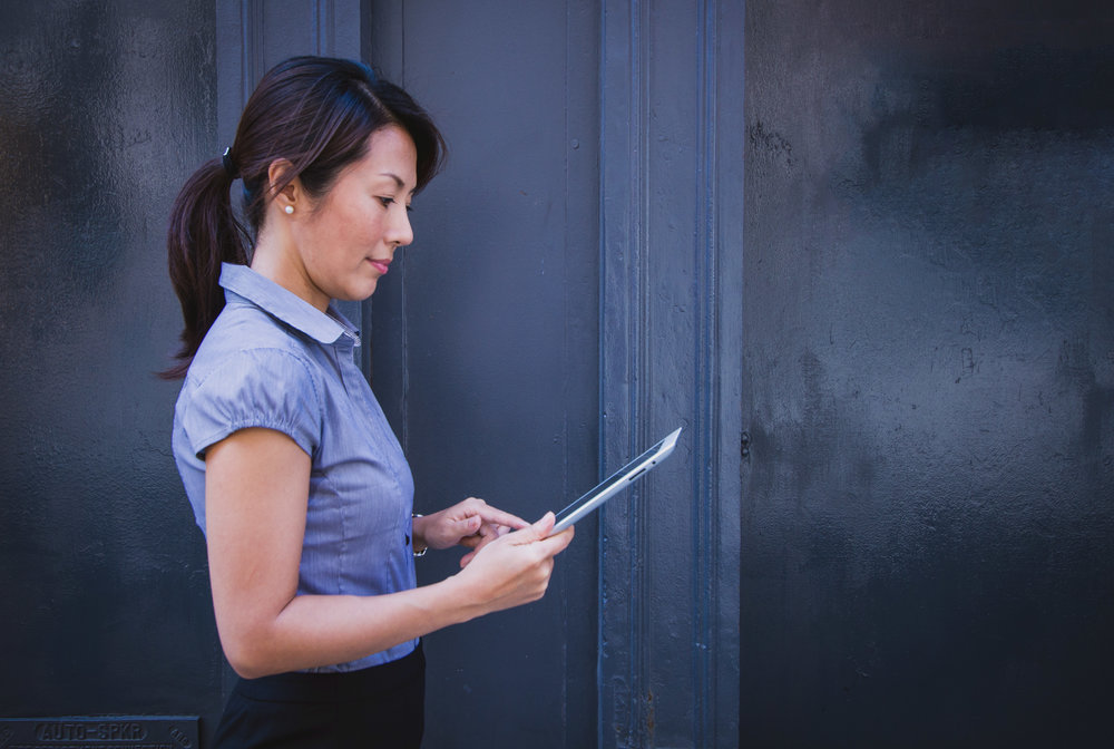 A woman is holding her tablet and smiling.