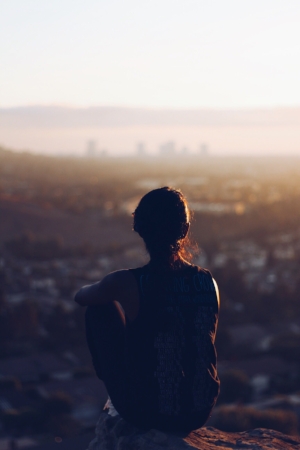 A person standing on top of a hill looking at the city.