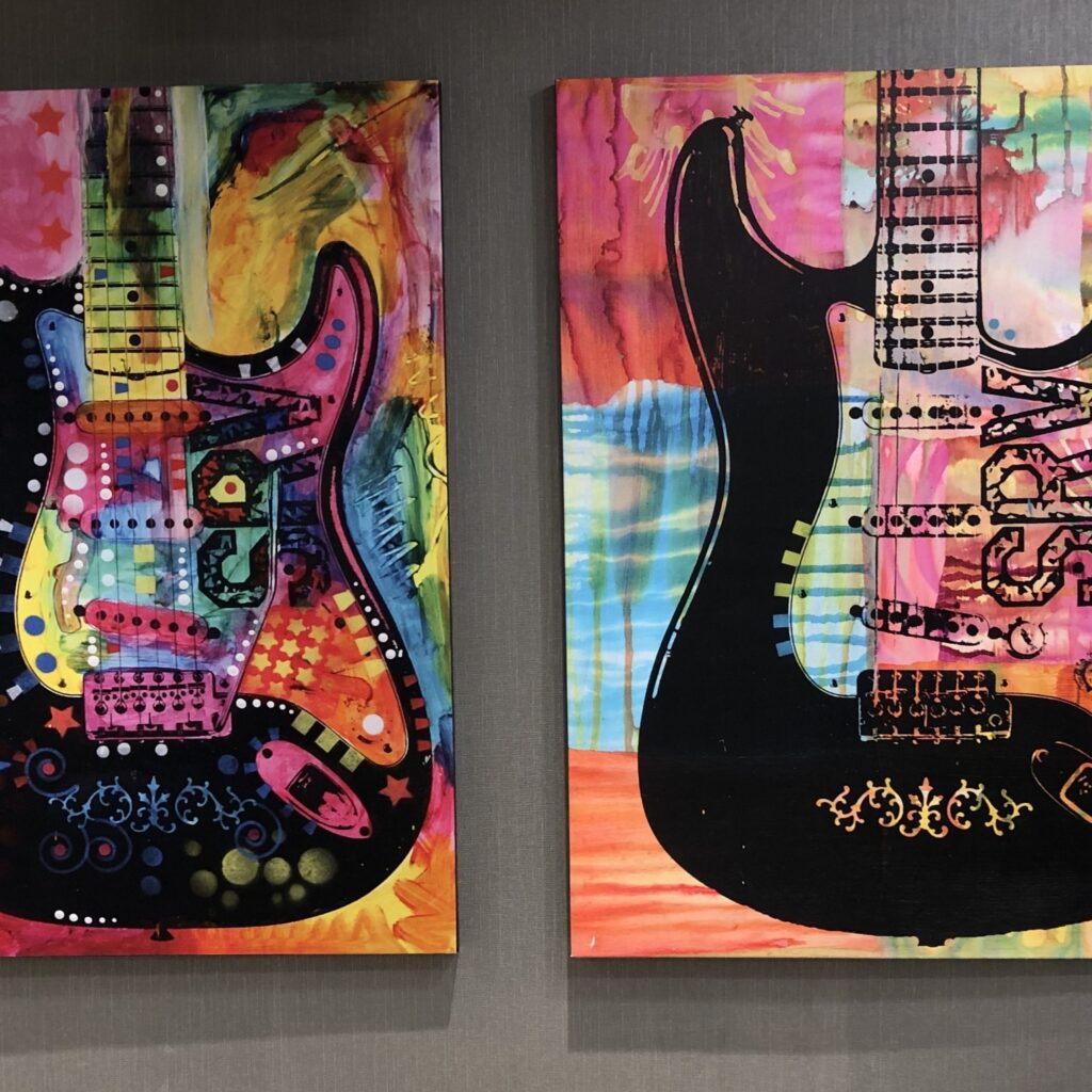 Two paintings of guitars are on display.